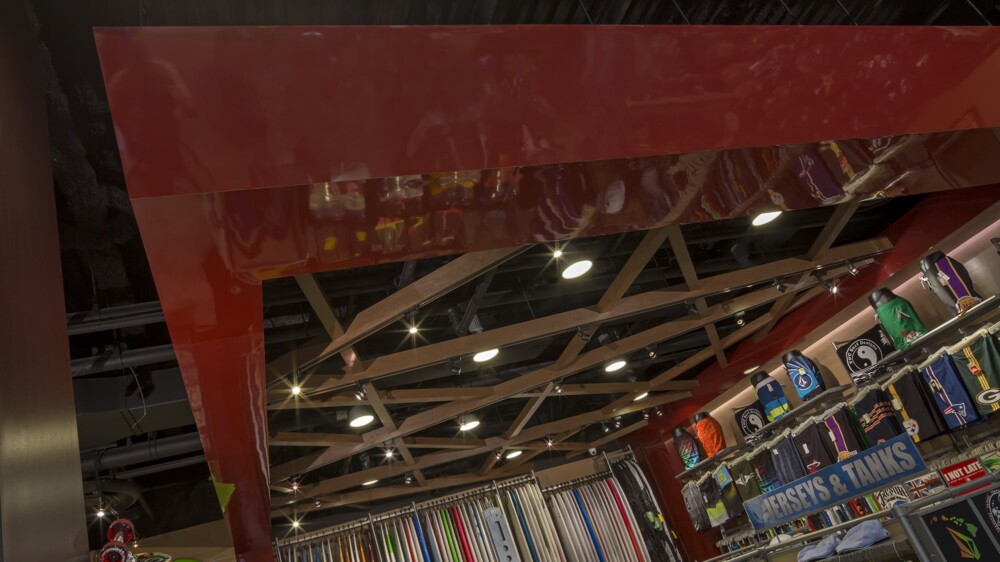 Contemporary ceiling design in a well-lit store showcasing surfboards and clothing.